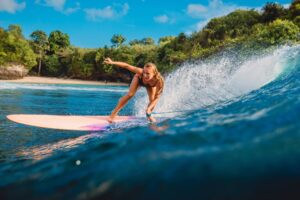 Bali Tour Beautiful surfer girl on surfboard. Woman in ocean during surfing in Bali