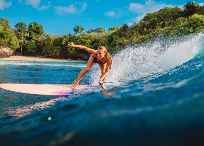 Bali Tour Beautiful surfer girl on surfboard. Woman in ocean during surfing in Bali