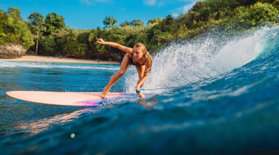 Bali Tour Beautiful surfer girl on surfboard. Woman in ocean during surfing in Bali